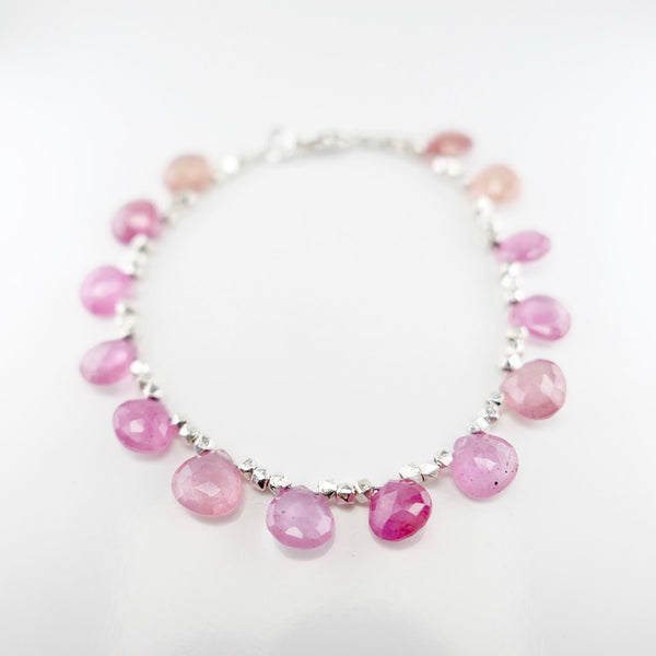 14 pink sapphire gems beaded with silver beads on a bracelet in perspective view.
