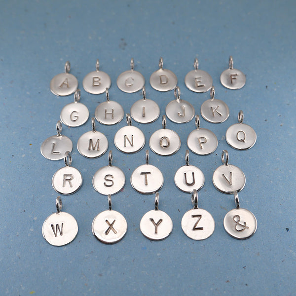 Top view showing handmade Sterling silver pendants letters A to Z including ampersand.