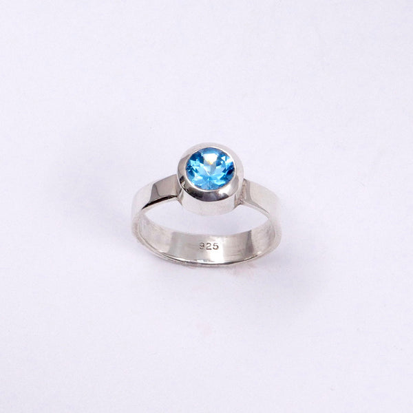 Close up view of handmade blue topaz silver ring with bevel setting, showing sterling silver 925 stamp on inside.