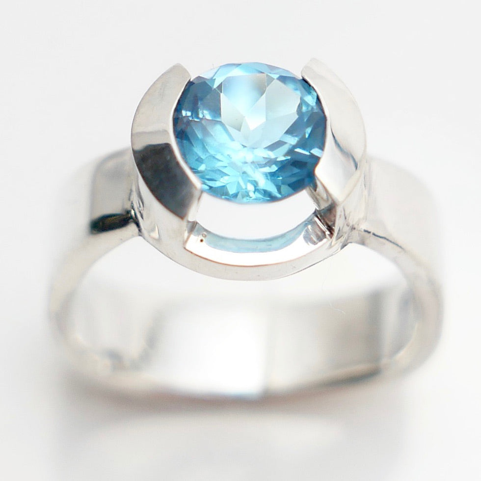 Close of blue topaz gem in silver two pronged setting ring.