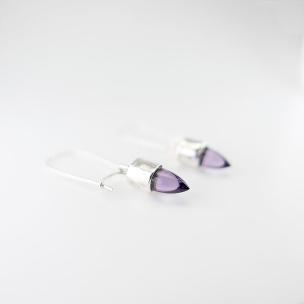 Side perspective view of silver hanging amethyst earrings. 
