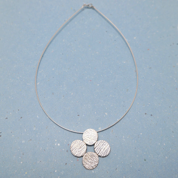 Full view of Sterling silver hammered dot pendant necklace on omeda chain. The handmade silver jewelry is unique as the hammered lines of the dots shows. 