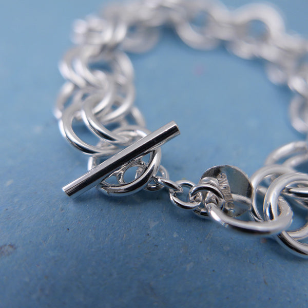 Close up of the bar clasp with the rest of the double ringed silver bracelet in perspective view.