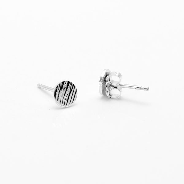 Silver hammered lines stud earrings showing one earring lying on its side to reveal the backing.