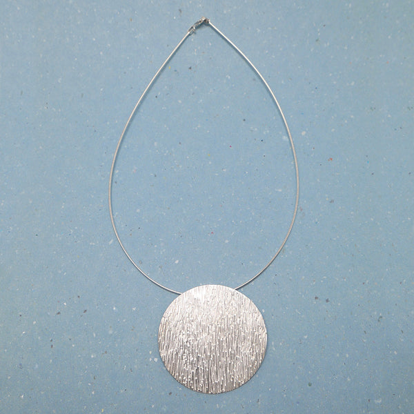 Top view of silver hammered disc necklace showing entire piece on wire chain.