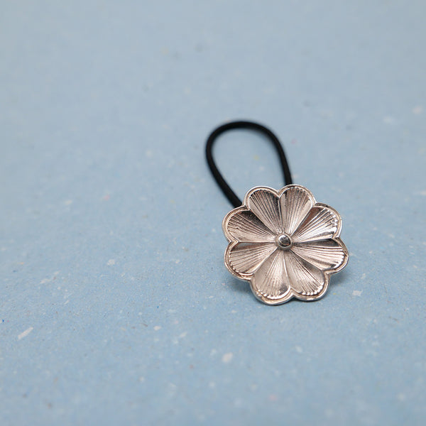 Close up of silver sakura flower jewelry hair tie inspired by Japanese cherry blossom.
