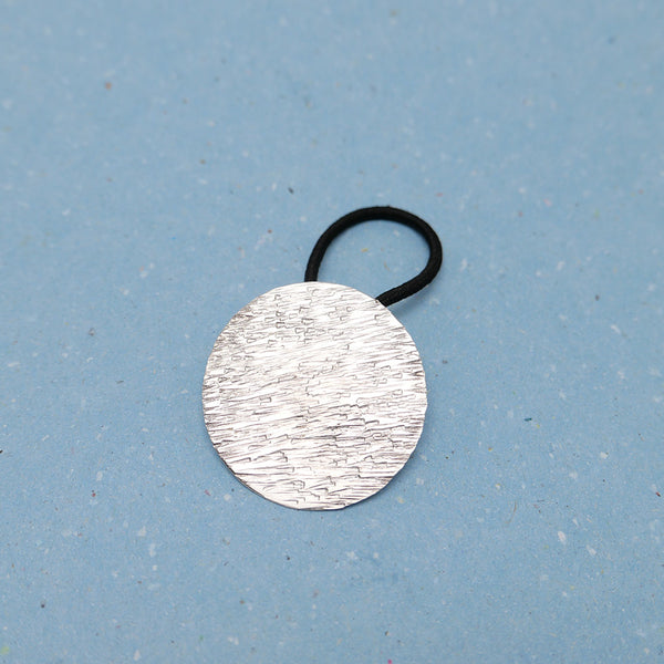 Close up of hammered lines silver hair tie, showing silversmith artisan craftsmanship.