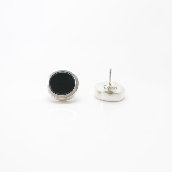 Silver Onyx dot earrings with one earring lying facedown to show the backing.