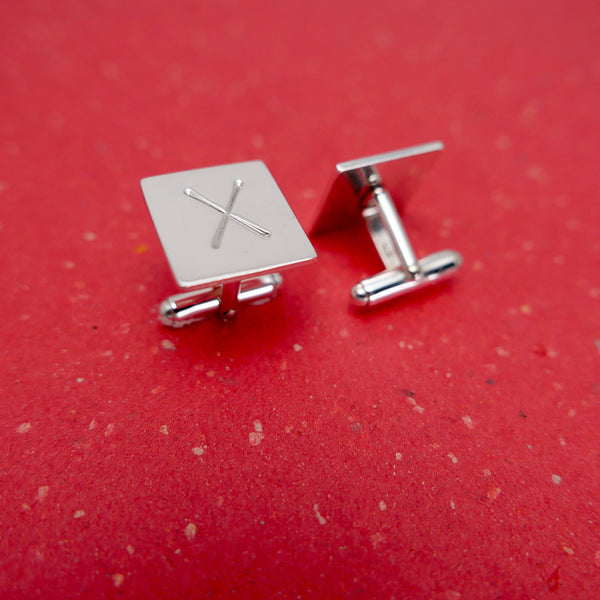 Handmade silver xo cufflinks with one on its side to show the backing clasp.